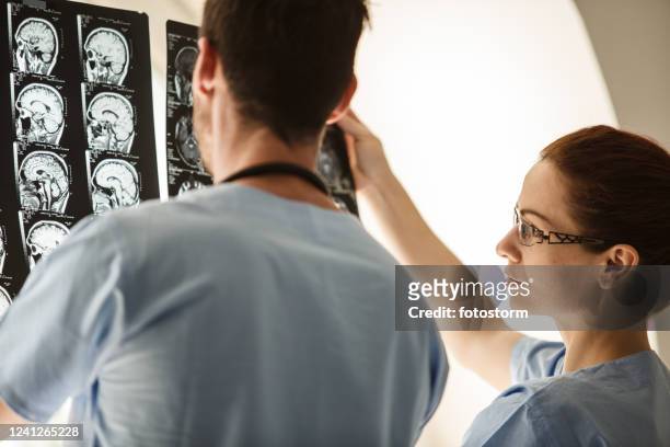 neurosurgeons reviewing mri scans of a brain tumor - skull xray no brain stock pictures, royalty-free photos & images
