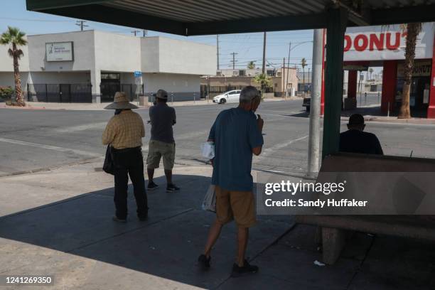 People stand under a shaded bus stop as the temperature reaches 115 degrees on June 12, 2022 in Calexico, California. Much of the Southwest is being...