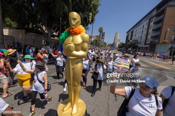 Paricipants march with an Oscar Awards statue at the annual Pride Parade on June 12, 2022 in the Hollywood section of Los Angeles, California. After...