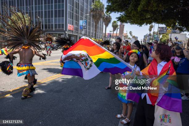 Traditional Aztec dancers pass a woman holding a rainbow version of the Mexican flag during the annual Pride Parade on June 12, 2022 in the Hollywood...