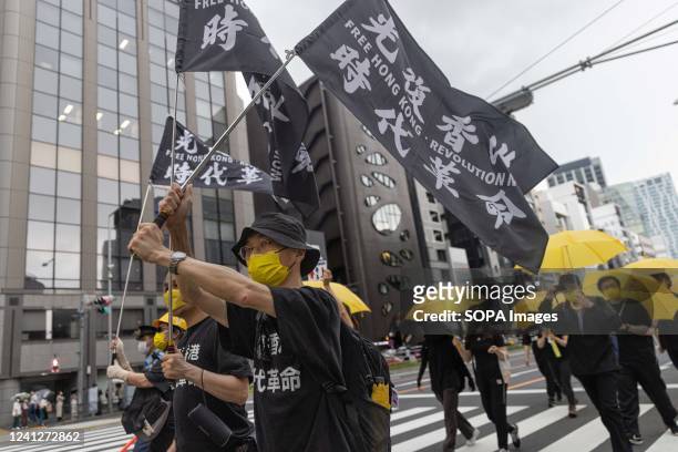 Demonstrators wave "Free Hong Kong" flags while marching through the streets of Shibuya during the three year anniversary of the June 12, 2019 Hong...