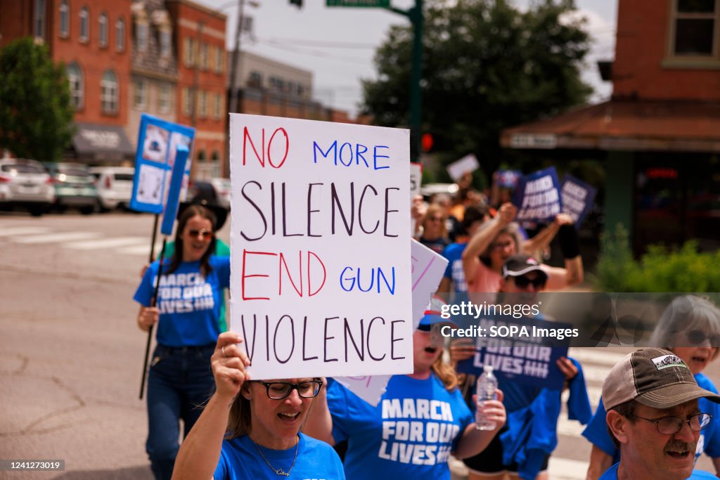A woman holds a placard that says No more silence end gun...