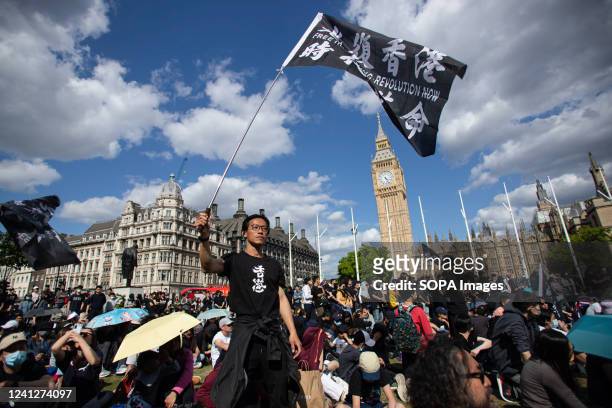 Pro-democracy demonstrator waves flag during a rally at Parliament square in London to mark the third anniversary of the start of massive...