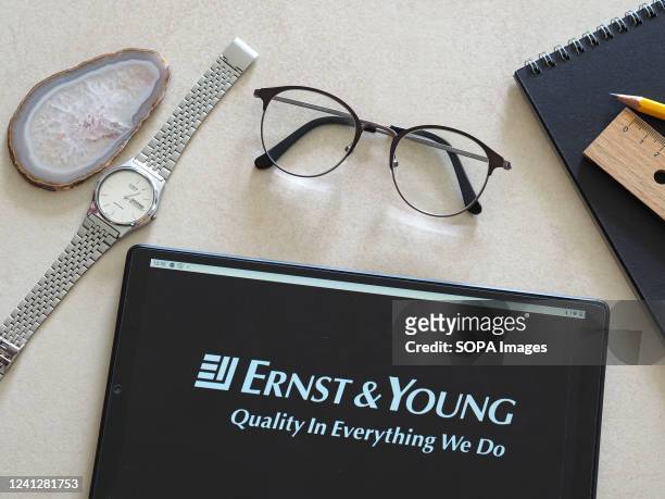 In this photo illustration, an Ernst & Young logo seen displayed on a tablet.