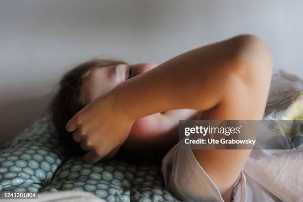 In this photo illustration Child lying on the bed hyding her face on May 09, 2022 in Bonn, Germany.