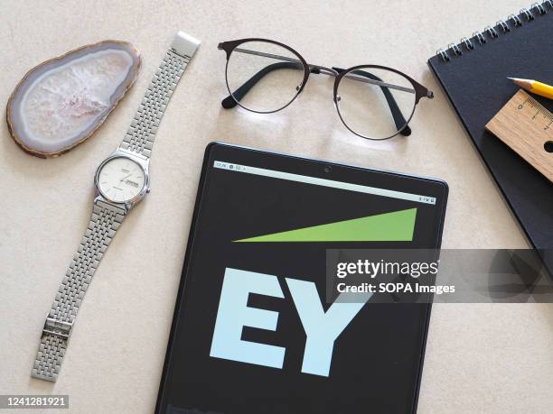 In this photo illustration, an Ernst & Young logo seen displayed on a tablet.