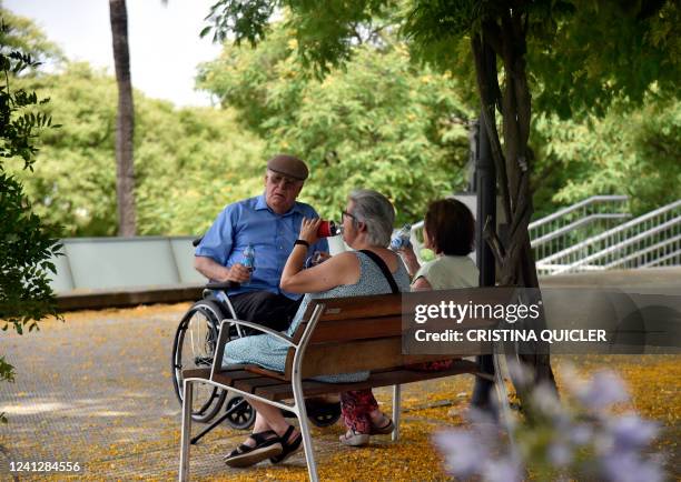 Elderly people drink in the shade to fight the scorching heat during a heatwave in Seville on June 13, 2022. - Spain was today already in the grips...