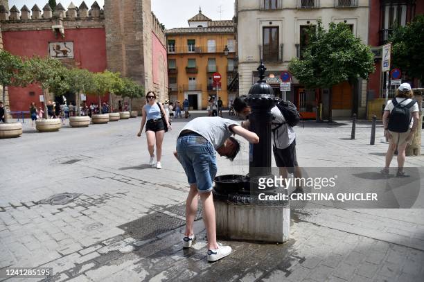 People cool off to fight the scorching heat during a heatwave in Seville on June 13, 2022. - Spain was today already in the grips of a heatwave...