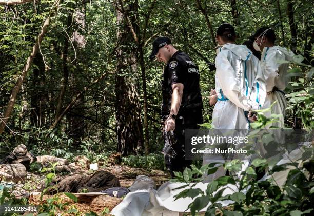 Policeman and excavation team work in a forest near Bucha, Ukraine during excavation of bodies of Ukrainian civilians murdered by Russian army The...