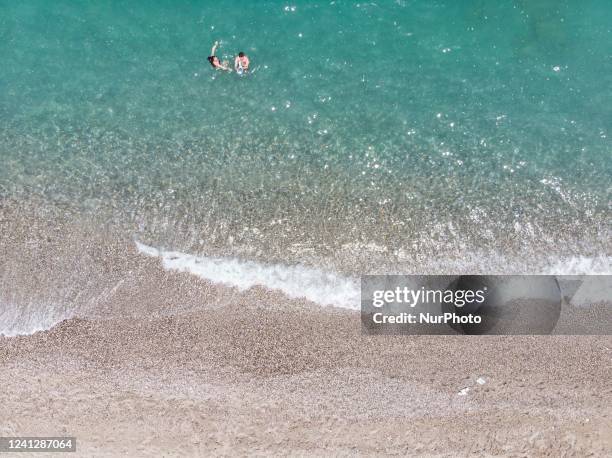 Aerial images from a drone of the coast of Rethymno town with the long beach and the beach bars in Creta island. People are seen enjoying the sun...