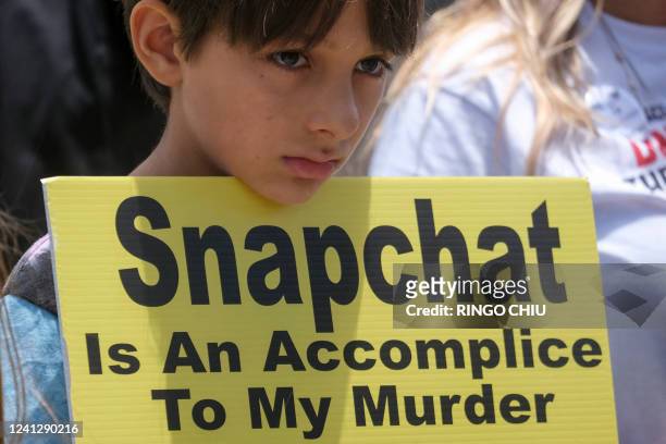 Young person holds a sign as people opposed to the sale of illegal drugs on Snapchat participate in a rally outside the company's headquarters to...