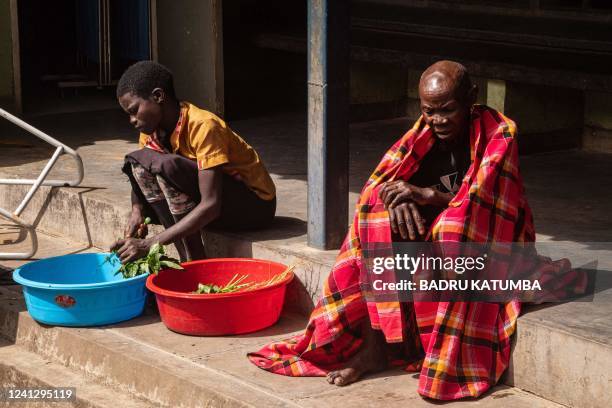 Girl cuts vegetables to cook for her sick grandmother at Kaabong hospital in Kaabong, Karamoja region, Uganda, on May 25, 2022. - More than half a...