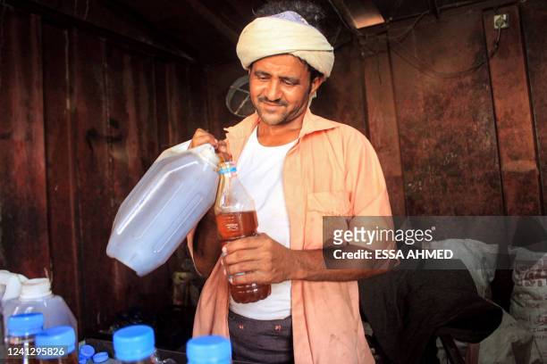 Man pours freshly-pressed sesame oil from a jerry can into a bottle to be sold, at an oil press in Yemen's northern district of Abs in Hajjah...