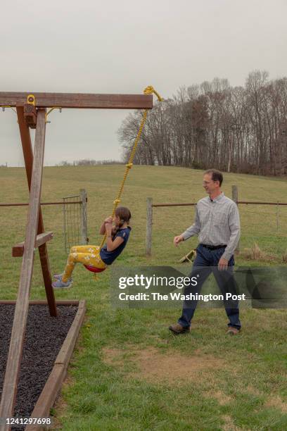 Preston Holley, right, swings his daughter Samantha outside their home in Limestone, Tennessee on Tuesday, March 15, 2022. Noise from a Bitcoin mine...