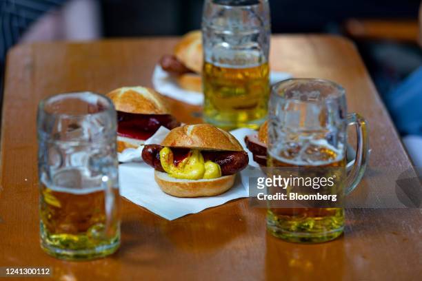 Glasses of beer and 'bratwurst' rolls at a beer garden in the Victuals Market in Munich, Germany, on Saturday, June 11, 2022. Confidence in the...