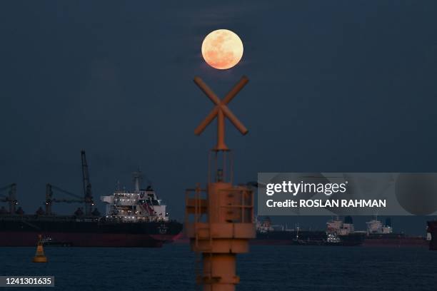 The full moon rises as the June 2022 "Strawberry Supermoon" in Singapore on June 14, 2022.