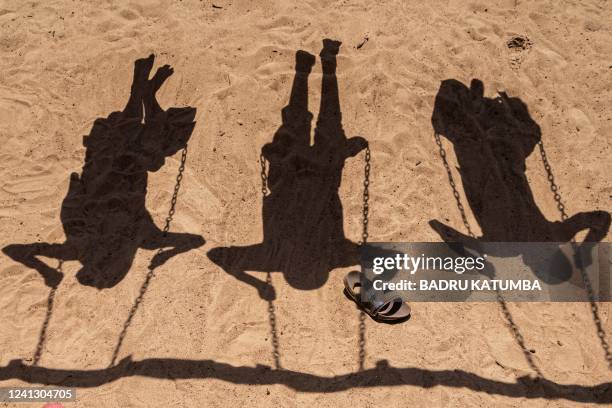 Shadow of child refugees from the Democratic Republic of Congo on swings are seen at the Nyakabande Transit Center in Kisoro, Uganda, June 7...