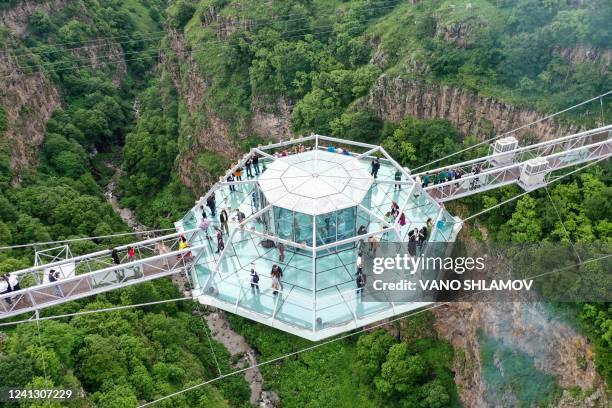 People attend the opening ceremony 240-meter long glass bridge over the Tsalka canyon, with a diamond-shaped café in the middle outside the city of...