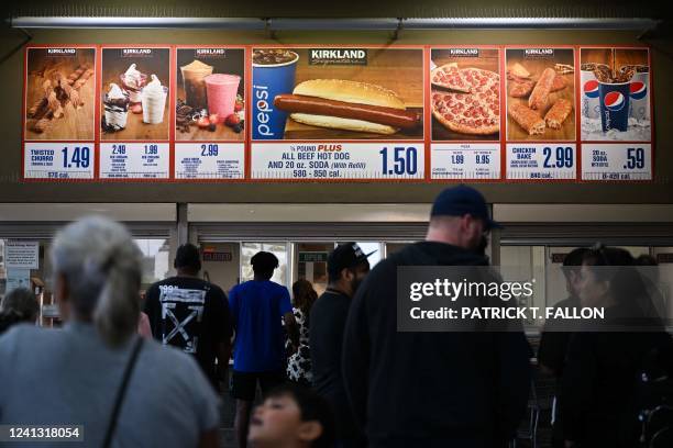 Customers wait in line to order below signage for the Costco Kirkland Signature $1.50 hot dog and soda combo, which has maintained the same price...