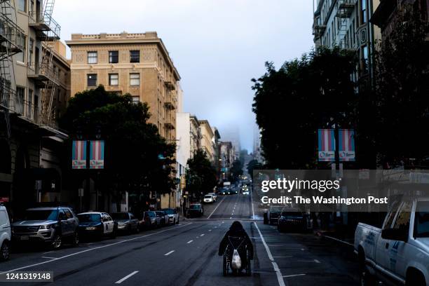 On a chilly foggy morning, a homeless man in a wheelchair finds it easier to move onto the street along Hyde Street then navigate through sidewalks...