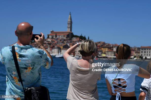 People take pictures of the city of Rovinj, on the west coast of the Istrian peninsula, on June 11, 2022. - Tourists are flocking back to Croatia...