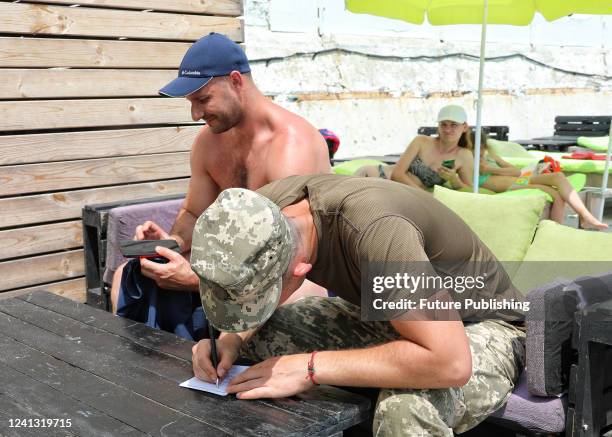 Serviceman issues a summons to appear at a military registration and enlistment office to a man during a raid on a beach in Odesa, southern Ukraine....