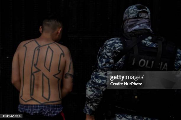 Police officer escorts a Barrio-18 gang member into a detention center on April 25, 2022 in San Salvador, El Salvador.
