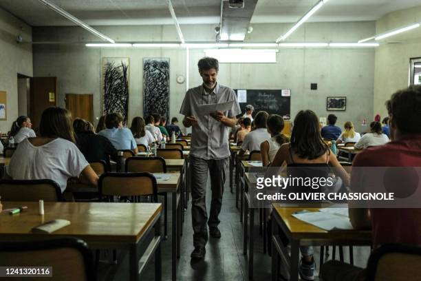 Teacher distributes copies ahead of the start of the philosophy test as part of the baccalaureat exams at the Sainte-Marie Les Maristes high school...