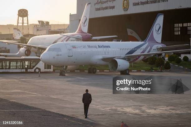 An unidentified man walks next to Iranian Meraj Airlines aircrafts at Tehrans International Mehrabad Airport on June 14, 2022.