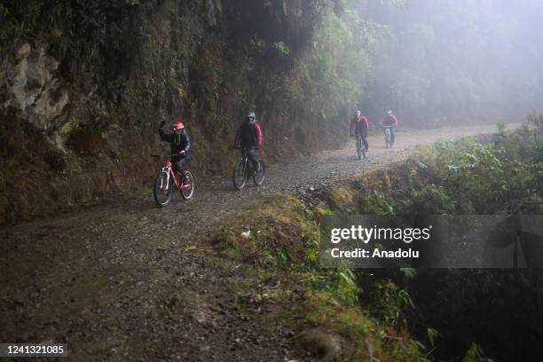 Tourists cycle down the Death Road in the middle of a dense fog in Los Yungas, La Paz, Bolivia on June 07, 2022. The Yungas Highway, also popularly...