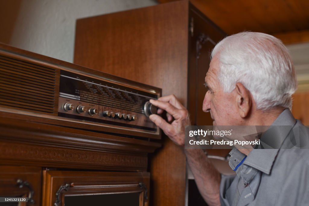 Portrait of senior man turning old lamp radio