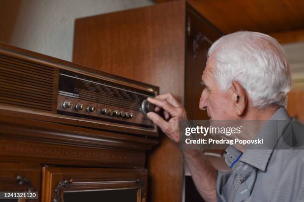 portrait of senior man turning old lamp radio - antique radio stock pictures, royalty-free photos & images