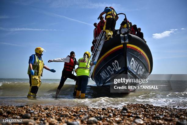 Royal National Lifeboat Institution's members of staff help migrants to disembark from one of their lifeboat after they were picked up at sea while...