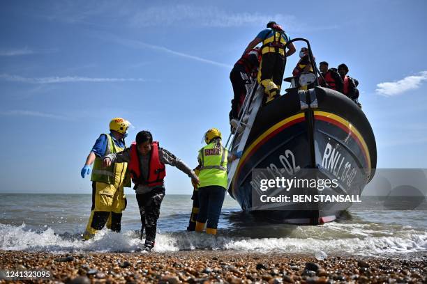 Royal National Lifeboat Institution's members of staff help migrants to disembark from one of their lifeboat after they were picked up at sea while...