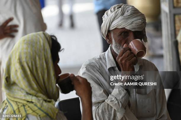 Men drink a cup of tea at a roadside restaurant in Islamabad on June 15, 2022. - A Pakistani minister has caused a storm in a teacup by urging...