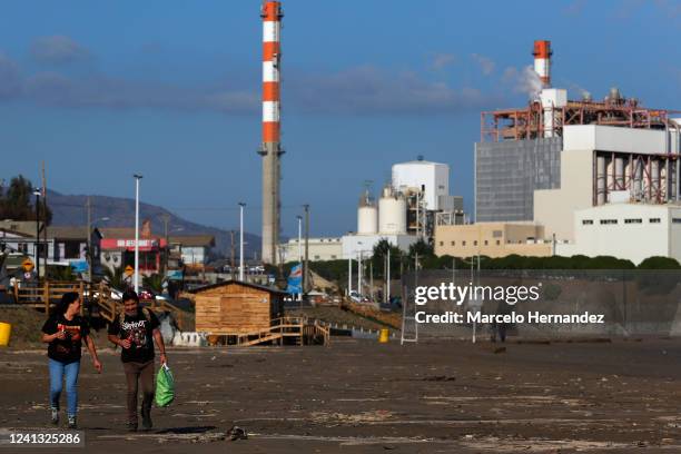 Couple walks along a closed beach next to oil pipelines of the Ventanas industrial park on June 14, 2022 in Puchuncavi, Chile. Due to the high...