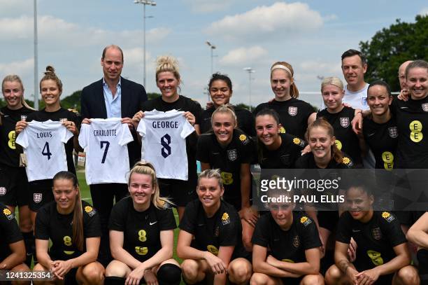 Britain's Prince William, Duke of Cambridge poses with the England's football jersey bearing the names of his three children and with the England's...
