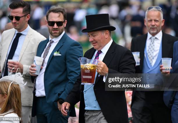 Racegoer carries a jug of Pimms as he attends the second day of the Royal Ascot horse racing meet, in Ascot, west of London on June 15, 2022.