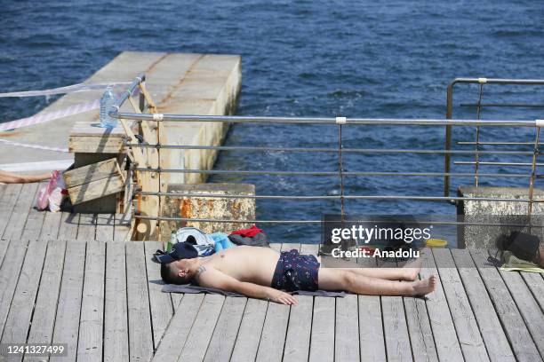 People rest in front of prohibition tapes, as swimming in the sea is prohibited due to the threat of mines, in Odessa, Ukraine in Odessa, Ukraine on...