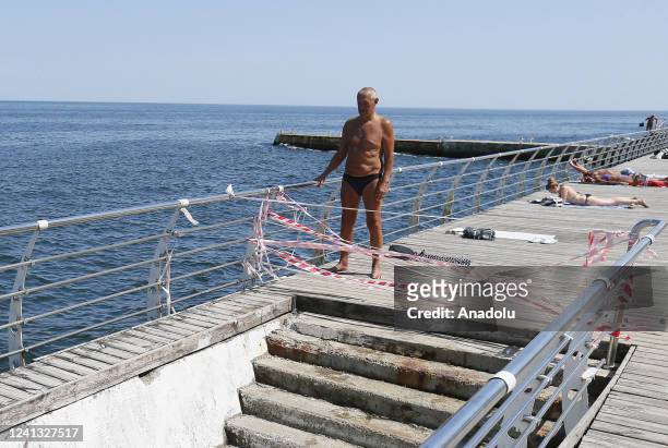 People rest in front of prohibition tapes, as swimming in the sea is prohibited due to the threat of mines, in Odessa, Ukraine in Odessa, Ukraine on...