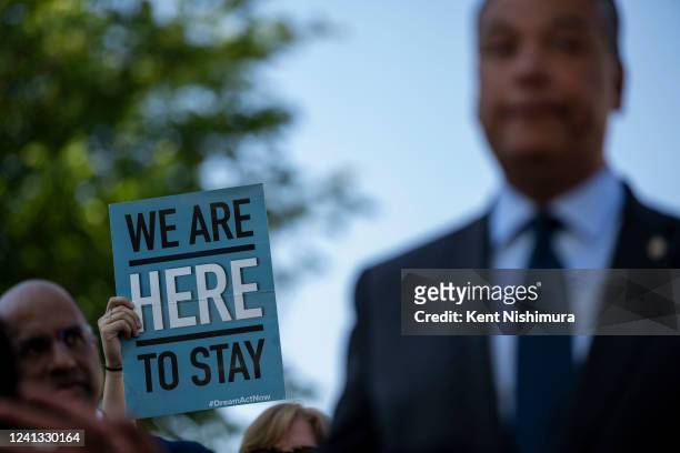 An activist holds up a sign as Sen. Alex Padilla speaks during a news conference marking the 10th anniversary of the passing of Deferred Action for...
