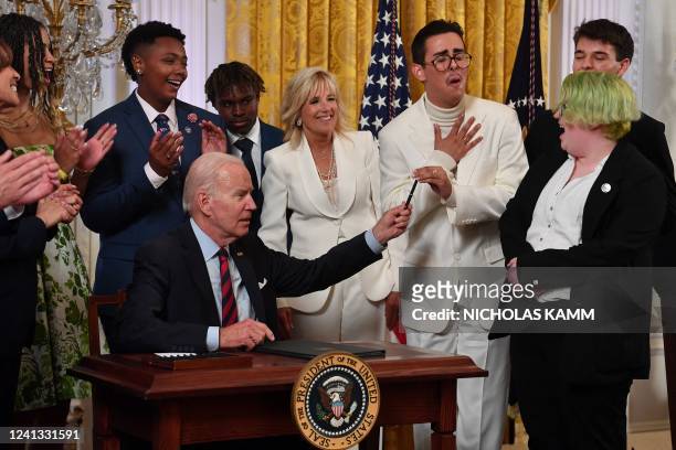 Youth Activist Javier Gomez reacts as US President Joe Biden hands him a pen after signing an Executive Order Advancing Equality for LGBTQI+...