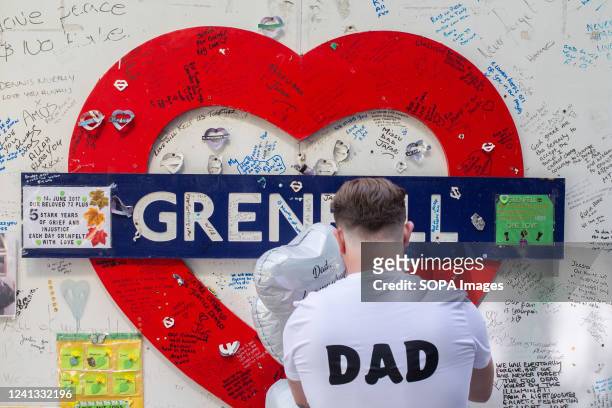 Man with Dad printed on his T-shirt is seen leaving a tribute in front of a wall surrounding Grenfell Tower in west London. Grenfell Tower fire...