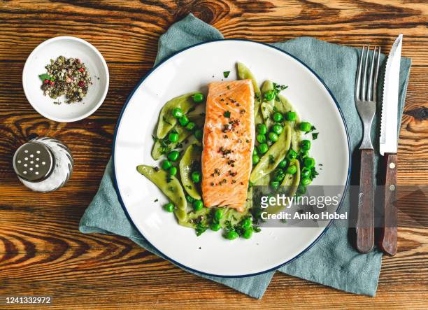 baked salmon with spinach pasta and green peas - rustic plate overhead stock pictures, royalty-free photos & images