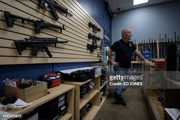 Shop owner Tony Hook stands behind a counter at RTD Arms & Sport in Goffstown, New Hampshire on June 2, 2022. - Smaller gun makers are booming in the...