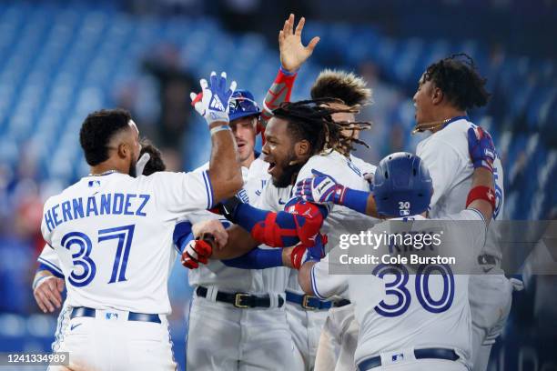 Vladimir Guerrero Jr. #27 of the Toronto Blue Jays is celebrated by teammates after hitting a walk-off RBI single in the 10th inning against the...