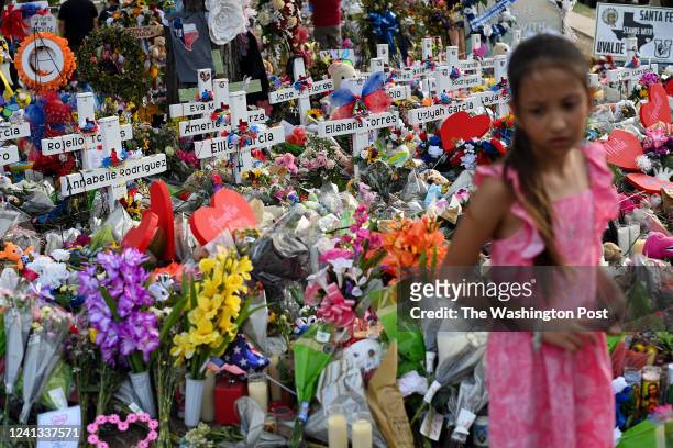 Girl stands next to crosses displayed at the memorial outside Robb Elementary School on May 31, 2022 in Uvalde, Texas. Salvador Rolando Ramos, an...