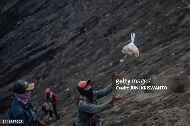 Villager catches an offering thrown by a member of the Tengger sub-ethnic group in the crater of the active Mount Bromo volcano as part of the Yadnya...