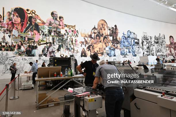 Artists of the lumbung collective of Indonesia work at a printing machine at a work by Baan Noorg Collaborative Arts and Culture from Thailand, at...