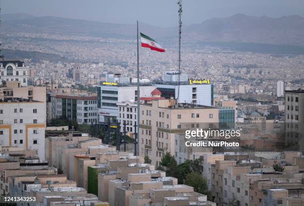 An Iranian flag waves while a view of residential and commercial buildings is pictured in northwestern Tehran on June 15, 2022.
